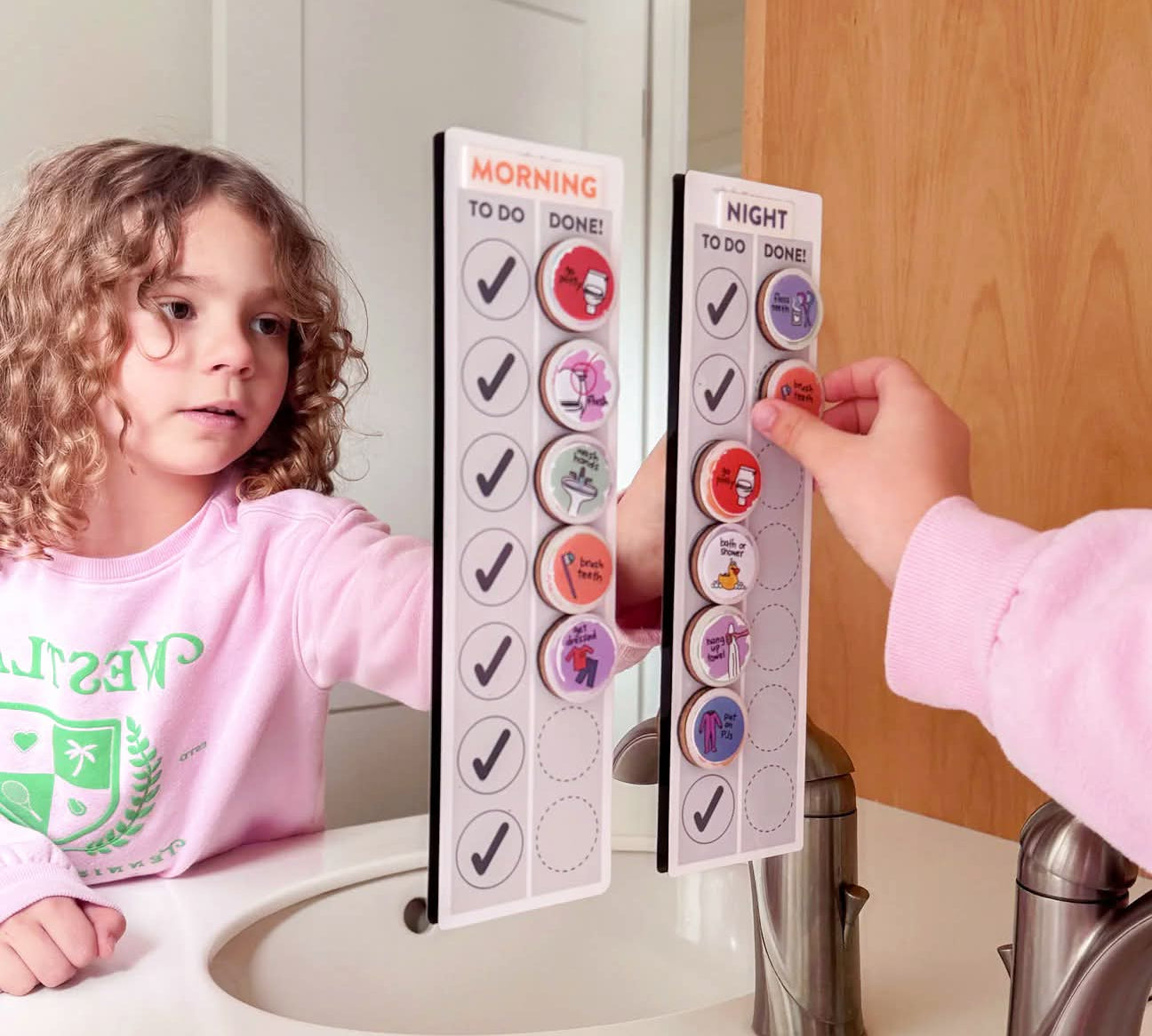 Child using a magnetic routine chart affixed to a bathroom mirror
