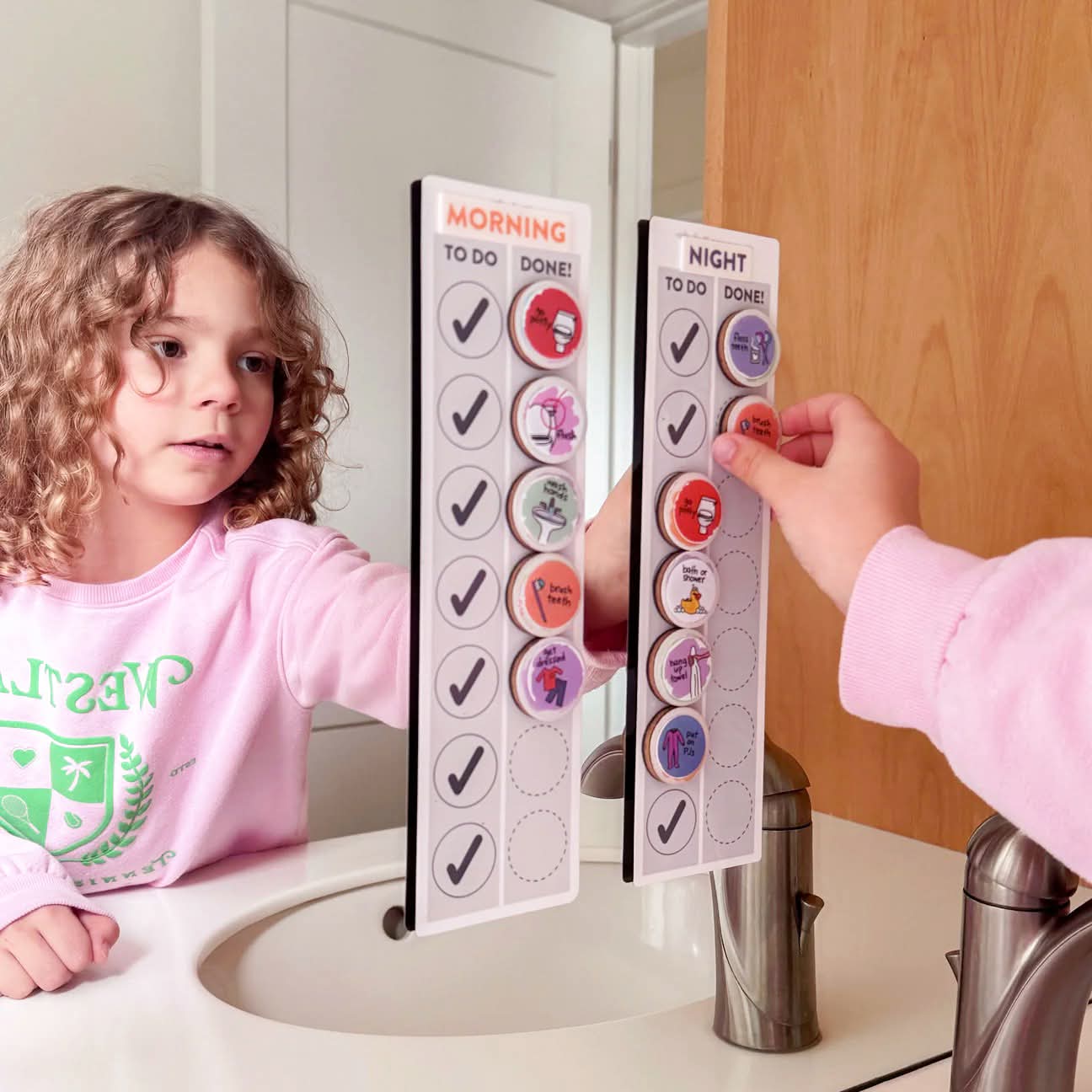 Child using a magnetic routine chart affixed to a bathroom mirror